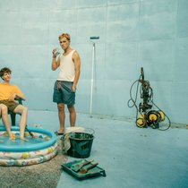 BlaBla (Sebastian Jakob Doppelbauer, l.), Carlo (Jeremias Meyer, M.) und Aydin (David Ali Rashed, r.) haben eine Güllegrube blau gestrichen und wollen daraus ihren eigenen Pool mit Beach basteln.