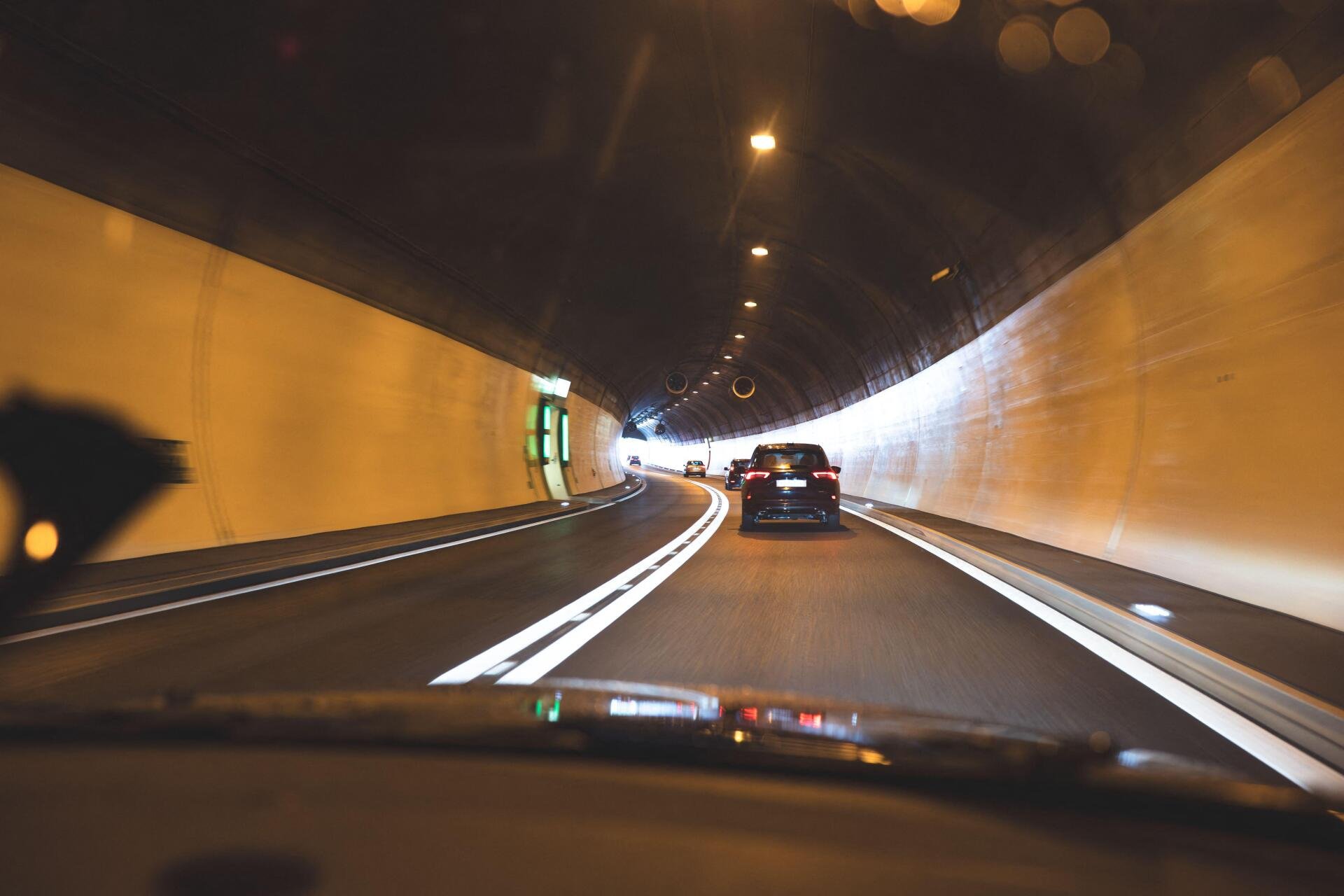 3EJ2249 Gotthard Tunnel, Switzerland, May 18, 2026. A forward-facing view from inside a car driving through a well-lit road tunnel, showing cars ahead in the